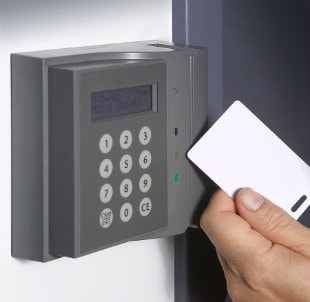 A workers hand swiping a digital card lock at an access control terminal