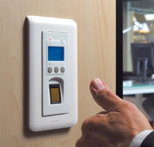 A workers thumb pressing on a fingerprint scanner at an access control terminal