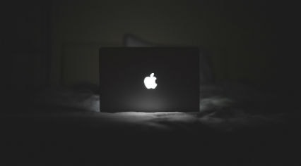 apple corporate logo illuminated on a laptop