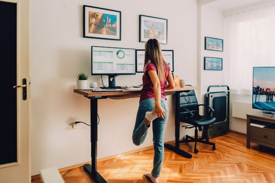 A woman standing at a computer desk in her home office